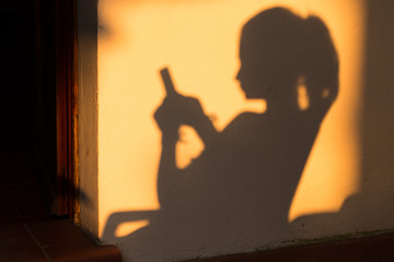 une jeune fille utilisant son smartphone en ombre chinoise sur un mur