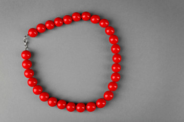 Stylish red beads on grey background