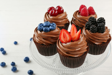 Glass stand with chocolate cupcakes on white table