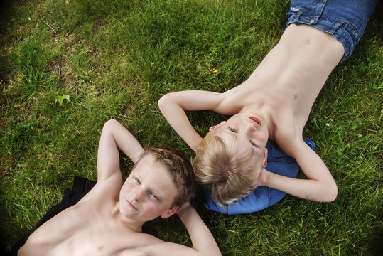 High angle view of twin brothers lying in backyard