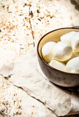 Mozzarella in bowl on old fabric.