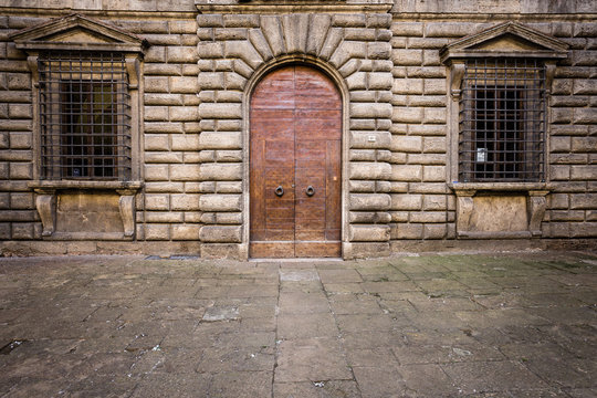 une lourde porte et deux fenêtres avec des barreaux sur un bâtiment public