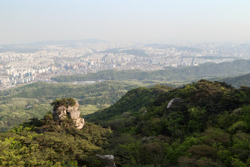 Obraz premium View of the city from above far away, crag and lush forest at the Bukhansan National Park in Seoul, South Korea.
