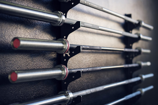 Close-up of weightlifting bars on racks in gym