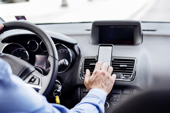 Cropped image of businessman using GPS on smart phone in car
