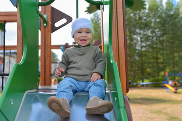 Fototapeta na wymiar Happy little toddler boy having fun sliding on playground
