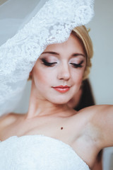 Portrait of beautiful bride with fashion veil posing at home at wedding morning. Makeup. Blondegirl with elegant hair styling. Wedding dress.