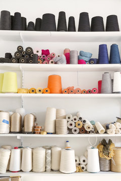 Colorful spools arranged on shelves at home