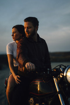 Couple riding motorcycle on field against sky