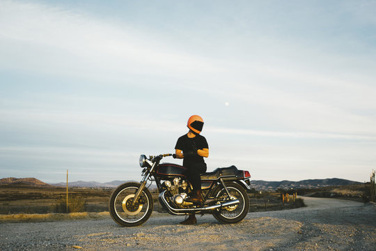 Low angle view of man wearing gloves while riding motorcycle at street against sky