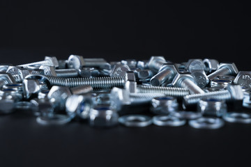 Shiny nuts and bolts on a black background