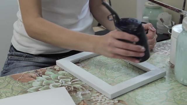 Girl dries hair dryer after painting handmade frame