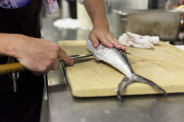A chef fillets fish before service. 