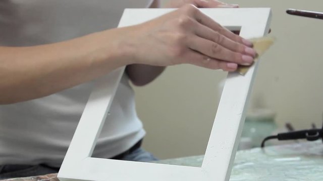 Girl cleans sandpaper handmade frame