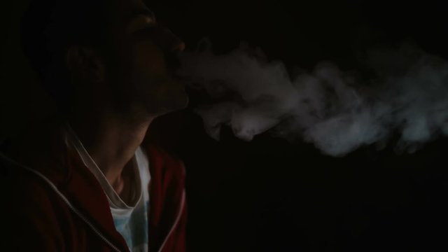 Man smokes hookah in a dark room. noir style