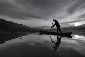 Silhouette asian fisherman on wooden boat