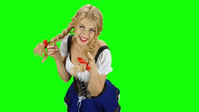 Woman in bavarian costume playing with her hair and laughs. Green screen