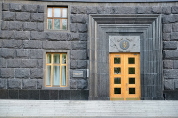 Entrance to the Government House of Ukraine. The coat of arms of Ukraine is above the door. Inscription on the board beside the entrance states this is the Government House of Ukraine.