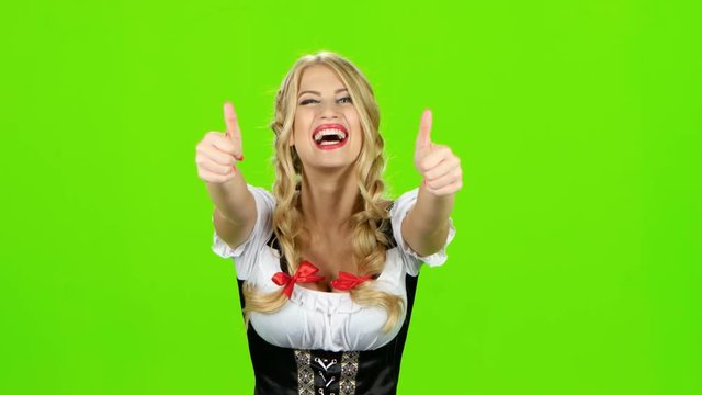 Woman in bavarian costume laughs and shows thumbs up. Green screen