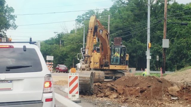 A backhoe digs at a road construction site.	