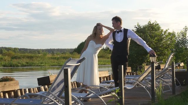 Bride and groom standing together on pier and smiling to each other