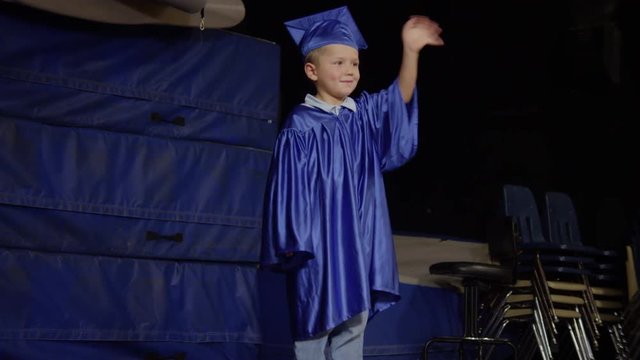 Little boy graduating and waving