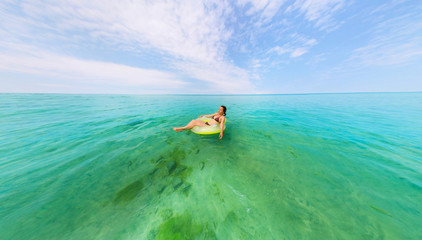 Girl in inflatable ring floating in the azure sea