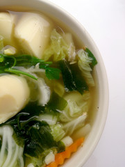 Clear Soup with Bean Curd , mix vegetable, Tofu and seaweed in white bowl on white background. Vegetarian Food, Healthy food, Thai food