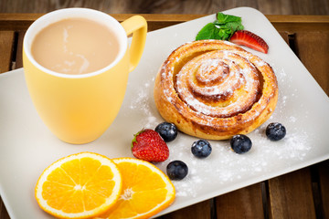 Cup of coffee and pastry on wooden background
