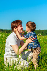 Fototapeta premium Young brunette with short hair playing with his son in the field