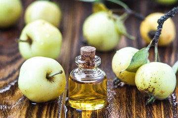 Apple vinegar in glass jar with ripe green wild apple fruits. Bottle of apple organic vinegar on wooden background. Healthy organic food.