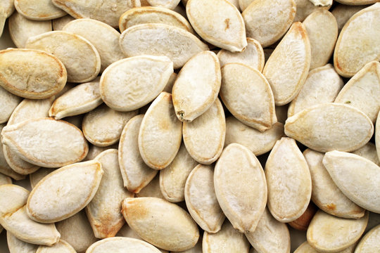 A close up image of whole pumpkin seeds