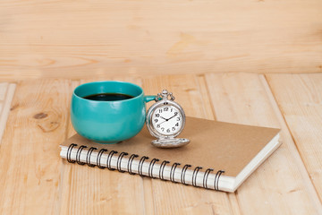 pocket watch and coffee cup on book