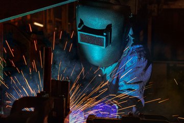 Welder is welding automotive part in factory