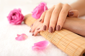 Female hands with brown manicure on wicker bamboo mat