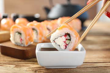 Tasty sushi roll with wooden chopsticks and sauce in bowl © Africa Studio