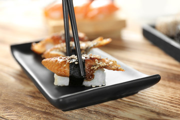 Tasty sushi with chopsticks, closeup