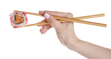 Female hand holding delicious sushi roll with chopsticks, isolated on white © Africa Studio