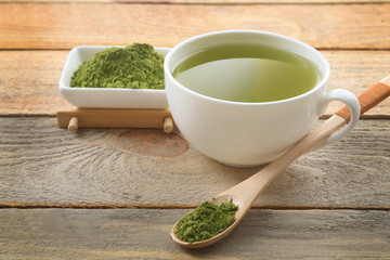 Cup of matcha tea on wooden background