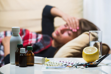 Sick woman lying on sofa under wool blanket