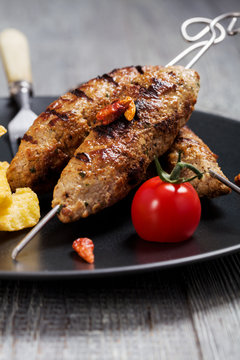 Barbecued kofta - kebeb with fries and vegetables on a plate.