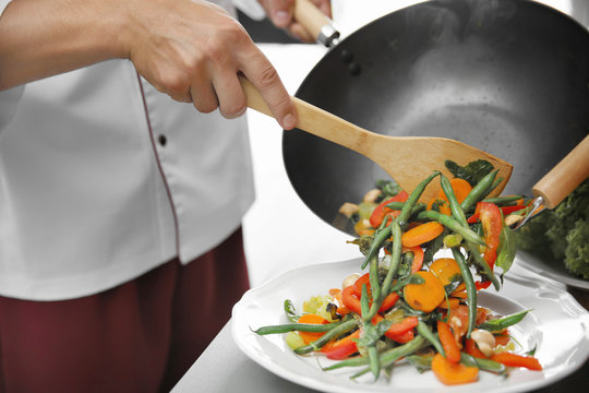 Female hand putting cooked vegetables on plate closeup
