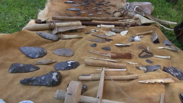 Tools and weapons made of flint and wood placed on fur in historic fair festival
