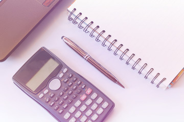 working desk with calculator and laptop, pen, notebook on white