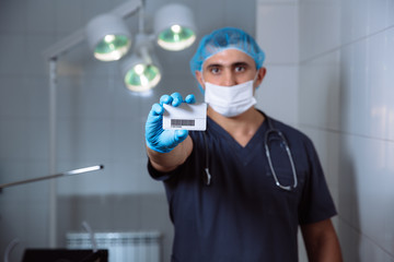 Fototapeta na wymiar Male doctor showing visiting card and looking at camera