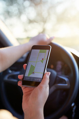 Woman in the car holding black mobile phone with gps map