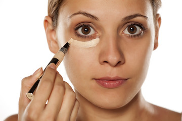 young beautiful woman applied concealer under the eyes