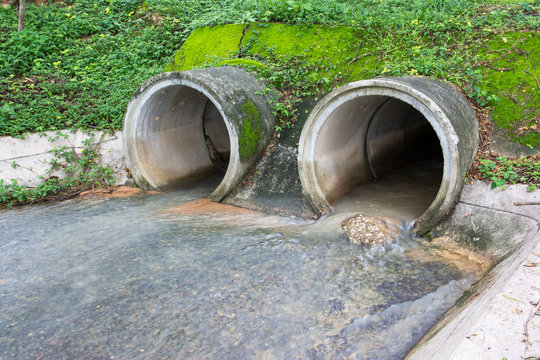 Water flowing from  drain pipe into a river