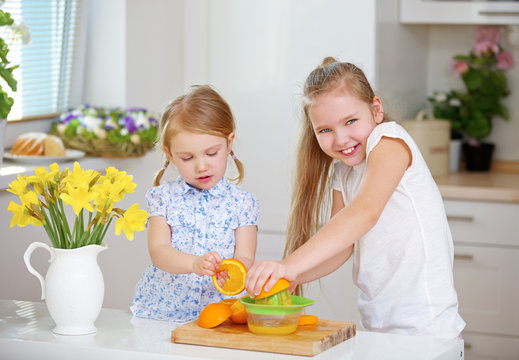 Kinder mit Entsafter und Orangen machen Orangensaft