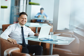 Fototapeta na wymiar Smiling businessman sitting in cafe